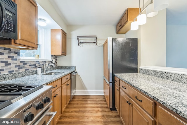 2504 Parkview Rd, Baltimore, MD 21207 - kitchen with appliances with stainless steel finishes, tasteful backsplash, light stone counters, light wood finished floors, and brown cabinetry