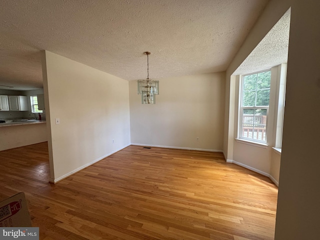 1809 Labrott Ln, Annapolis, MD 21401 - unfurnished dining area with light wood finished floors, a chandelier, and a textured ceiling