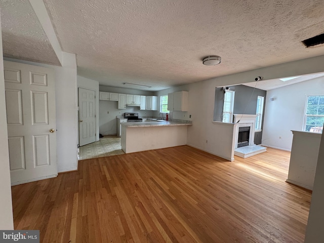 1809 Labrott Ln, Annapolis, MD 21401 - kitchen featuring light wood-style flooring, a peninsula, stainless steel range with electric stovetop, a textured ceiling, and open floor plan