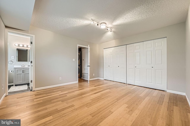 11921 Tarragon Rd Unit F, Reisterstown, MD 21136 - unfurnished bedroom featuring a textured ceiling, rail lighting, light wood finished floors, a closet, and connected bathroom