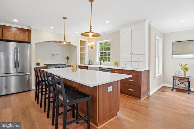 3722 13th St NE, Washington, DC 20017 - kitchen with stainless steel appliances, light wood-style floors, light countertops, a breakfast bar, and crown molding