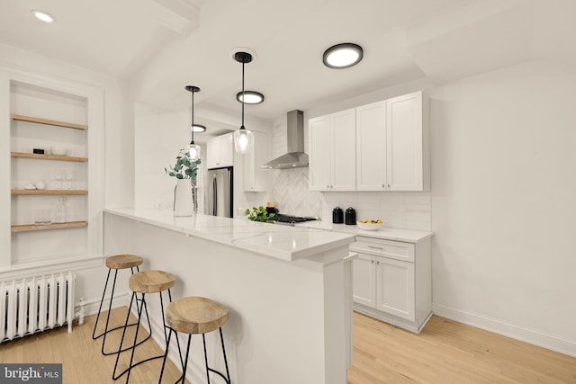 1371 Perry Pl NW, Washington, DC 20010 - kitchen with radiator heating unit, wall chimney range hood, a kitchen bar, light wood finished floors, and recessed lighting