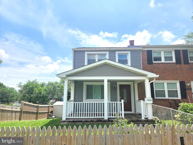 9765 Bird Riv, Middle River, MD 21220 - view of front facade featuring covered porch, brick siding, and a fenced front yard