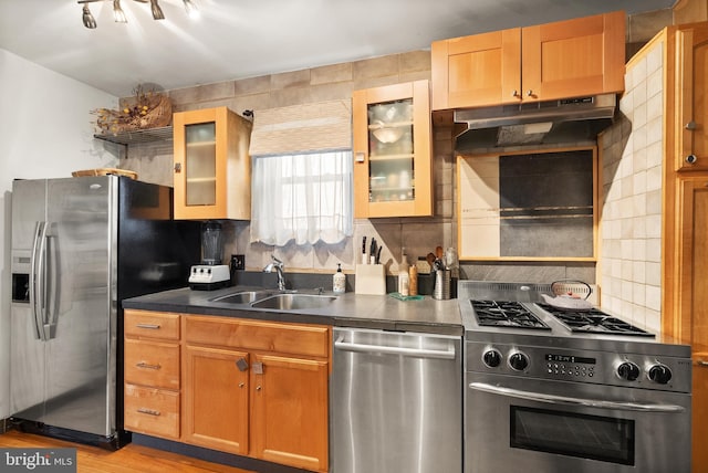 2515 17th St NE, Washington, DC 20018 - kitchen with appliances with stainless steel finishes, under cabinet range hood, dark countertops, decorative backsplash, and light wood-style floors