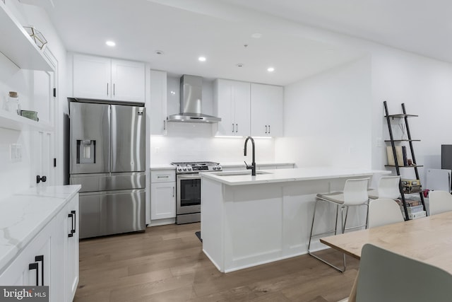 3317 16th St NW Unit 2, Washington, DC 20010 - kitchen featuring appliances with stainless steel finishes, wall chimney range hood, wood finished floors, light stone counters, and white cabinetry