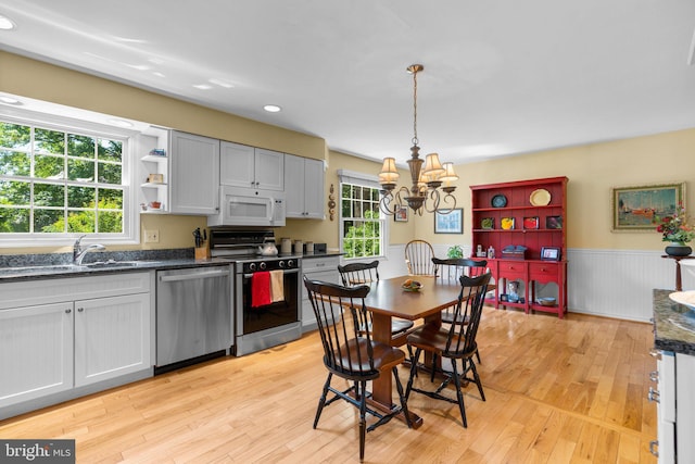 6162 Commadore Ct, Columbia, MD 21045 - kitchen with stainless steel dishwasher, white microwave, range, a chandelier, and light wood finished floors
