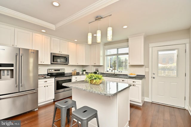 1103 Morse St NE, Washington, DC 20002 - kitchen with appliances with stainless steel finishes, white cabinets, dark wood finished floors, ornamental molding, and a breakfast bar