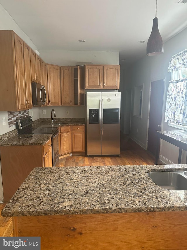 3709 Chesholm Rd, Baltimore, MD 21216 - kitchen featuring stainless steel appliances, dark stone countertops, light wood-style flooring, and brown cabinets