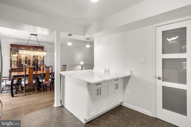 52 Anna Ct Unit 275, Gaithersburg, MD 20877 - kitchen featuring light stone countertops, dark tile patterned floors, white cabinetry, decorative light fixtures, and a peninsula