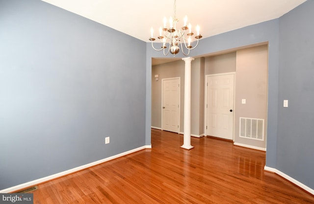 1007 Wright Ct, Fredericksburg, VA 22401 - unfurnished dining area featuring wood finished floors, a chandelier, and decorative columns