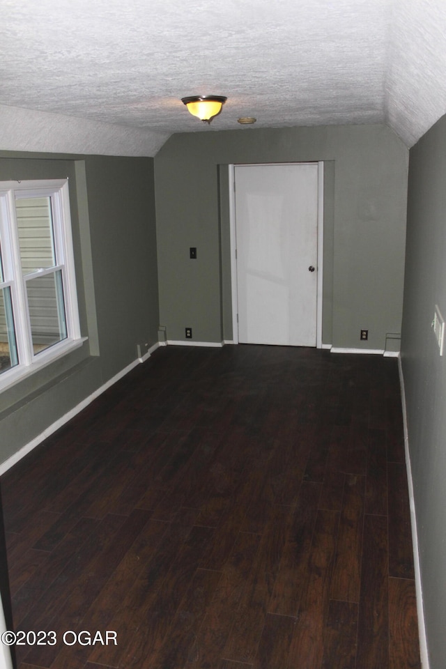 empty room with lofted ceiling, a textured ceiling, and dark hardwood / wood-style flooring