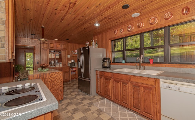 kitchen featuring white appliances, wooden walls, sink, dark tile flooring, and wood ceiling