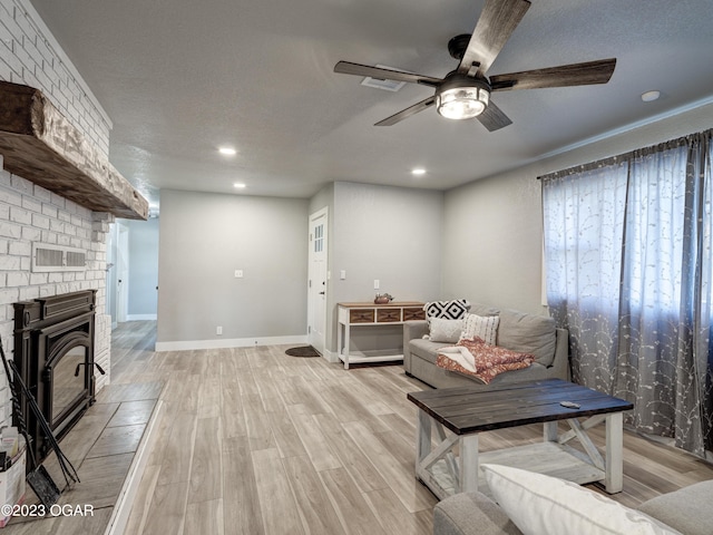 living room featuring ceiling fan, a brick fireplace, light hardwood / wood-style flooring, and brick wall