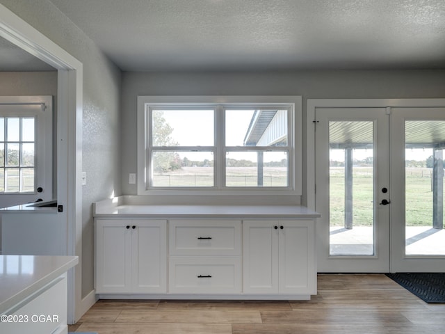 doorway with french doors, a textured ceiling, and light wood-type flooring