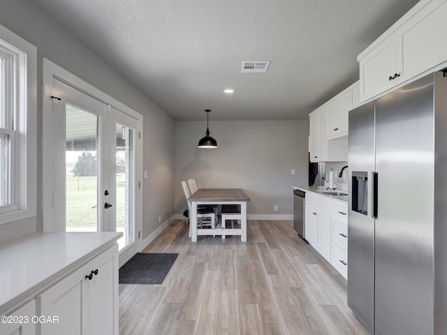 kitchen with sink, hanging light fixtures, white cabinets, stainless steel appliances, and light wood-type flooring