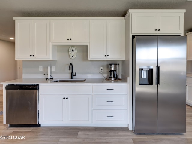 kitchen featuring light hardwood / wood-style flooring, white cabinetry, appliances with stainless steel finishes, and sink