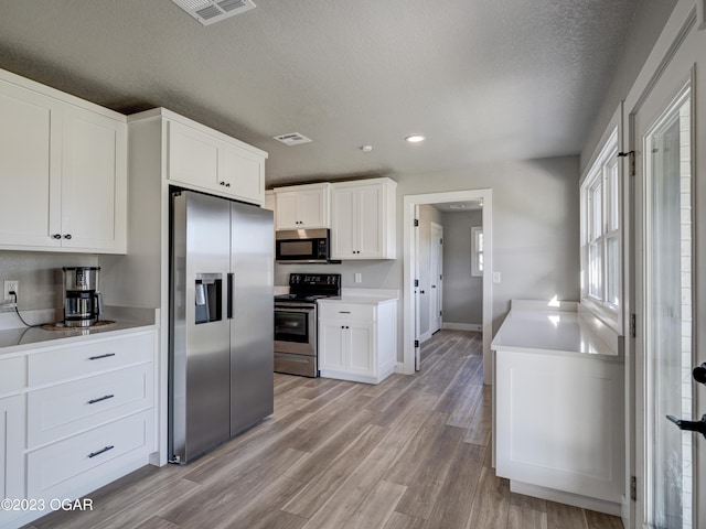 kitchen with white cabinetry, light hardwood / wood-style floors, a textured ceiling, and stainless steel appliances