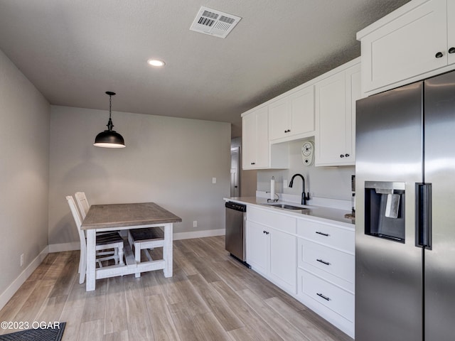 kitchen with pendant lighting, light hardwood / wood-style floors, appliances with stainless steel finishes, and sink