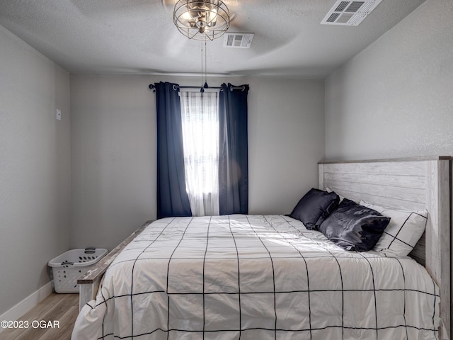 bedroom featuring a textured ceiling, light hardwood / wood-style floors, and ceiling fan