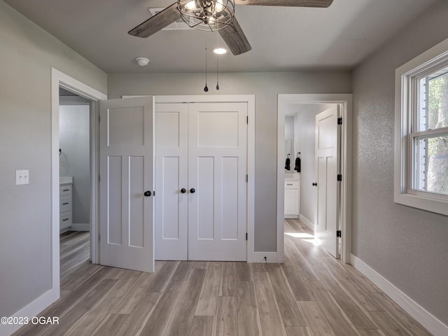 unfurnished bedroom with light hardwood / wood-style floors, a closet, ceiling fan, and ensuite bathroom