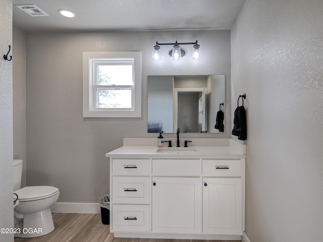 bathroom with vanity, a textured ceiling, wood-type flooring, and toilet