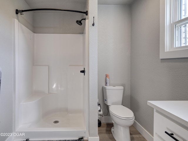 bathroom with walk in shower, toilet, vanity, and wood-type flooring