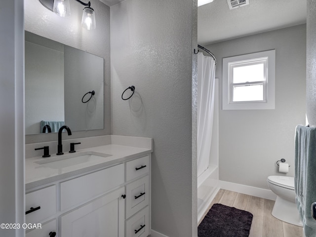 full bathroom featuring toilet, a textured ceiling, vanity, wood-type flooring, and shower / tub combo with curtain