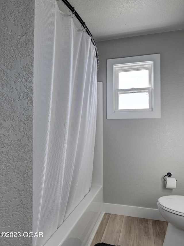 bathroom featuring shower / tub combo, toilet, a textured ceiling, and wood-type flooring