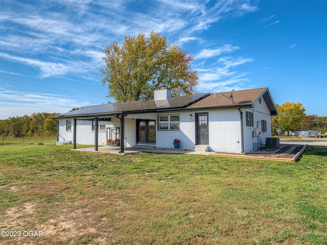 rear view of property with central air condition unit, a lawn, and a patio