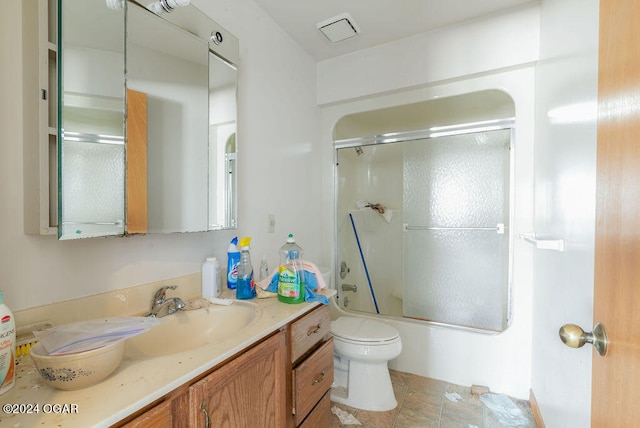 full bathroom with tile flooring, vanity, toilet, and bath / shower combo with glass door