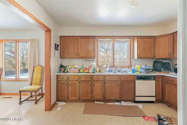 kitchen featuring white dishwasher, sink, and light tile floors