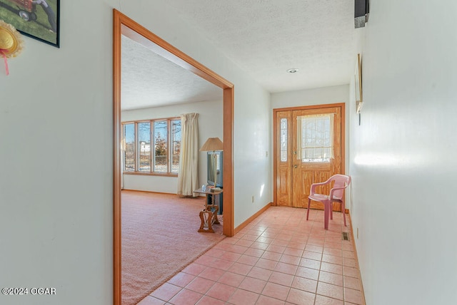 entrance foyer featuring a textured ceiling and light colored carpet