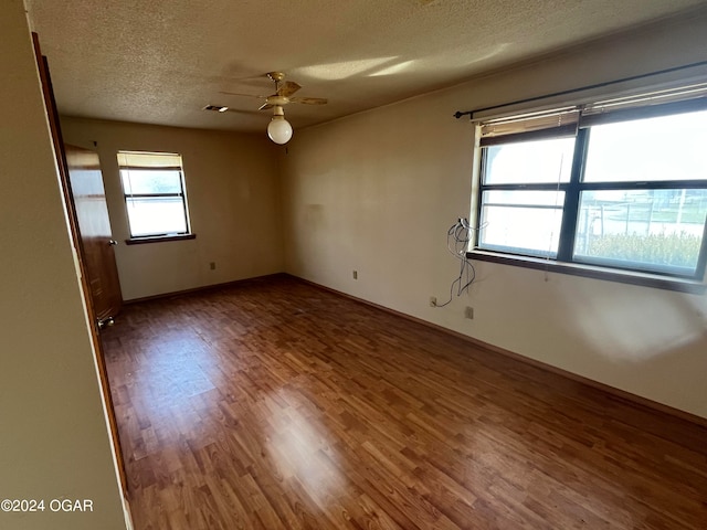 spare room featuring plenty of natural light, hardwood / wood-style floors, ceiling fan, and a textured ceiling