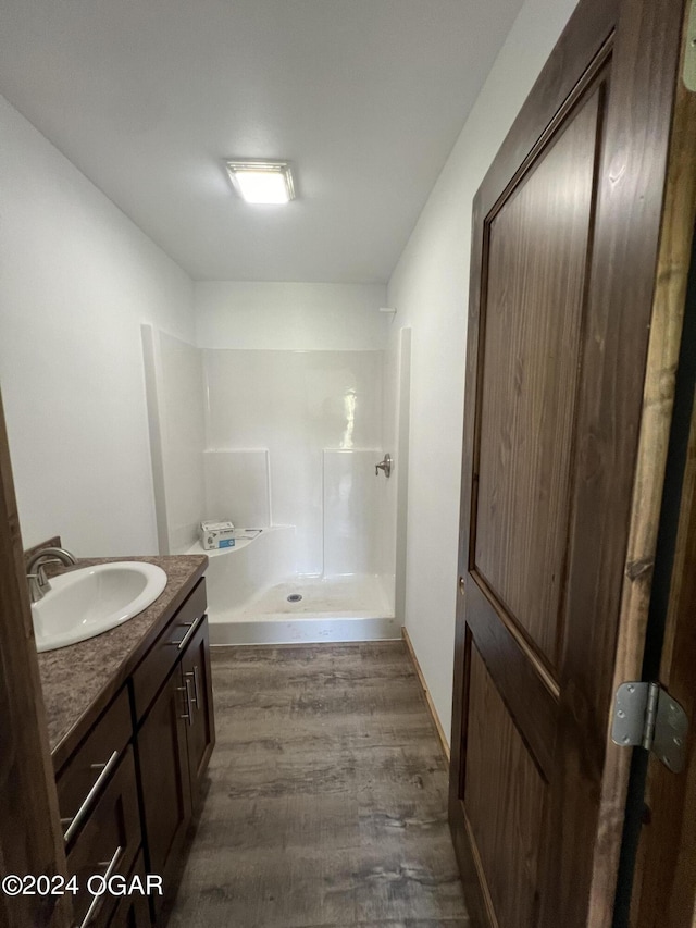 bathroom with walk in shower, vanity, and hardwood / wood-style floors