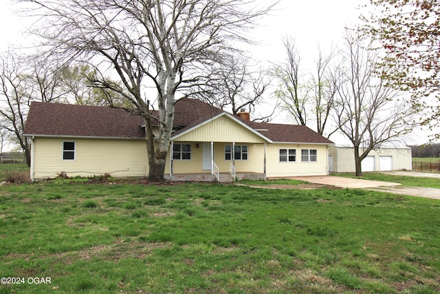 view of front facade featuring a front yard, an outdoor structure, covered porch, and a garage