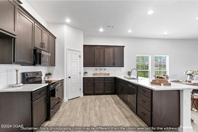 kitchen featuring dark brown cabinetry, black appliances, sink, kitchen peninsula, and light hardwood / wood-style flooring