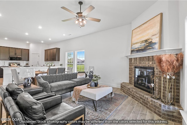 living room featuring ceiling fan, sink, and a brick fireplace