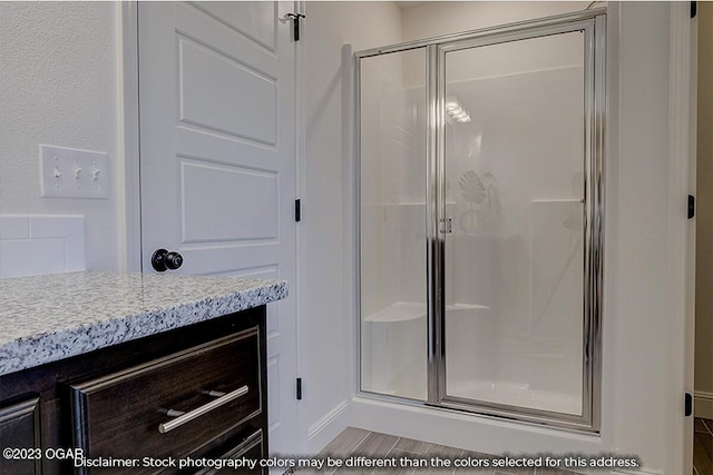 bathroom featuring a shower with door and vanity