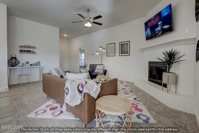 living room featuring light carpet, ceiling fan, and a brick fireplace