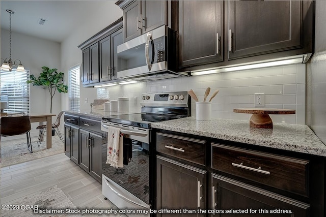 kitchen featuring light stone counters, tasteful backsplash, hanging light fixtures, stainless steel appliances, and an inviting chandelier