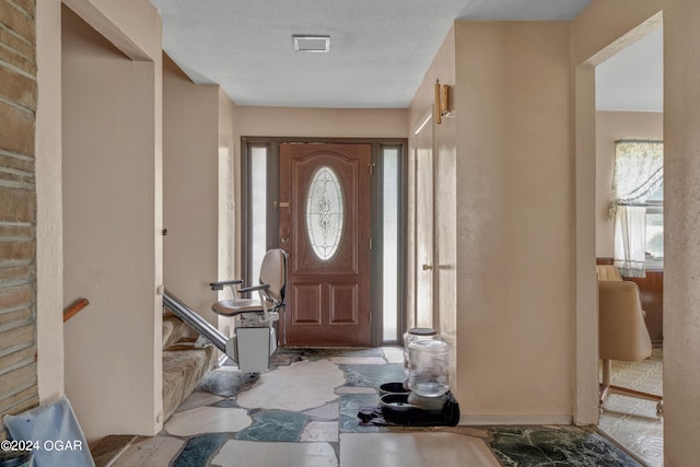 entryway with tile floors and a textured ceiling