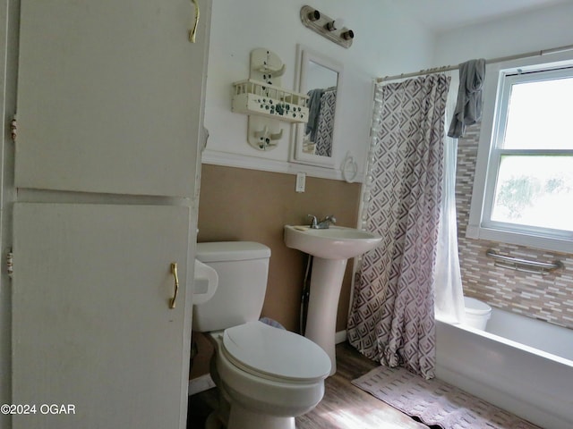 bathroom featuring wood-type flooring, toilet, and shower / tub combo