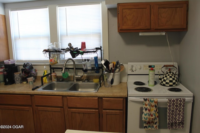 kitchen featuring a sink, brown cabinets, white electric range, and light countertops