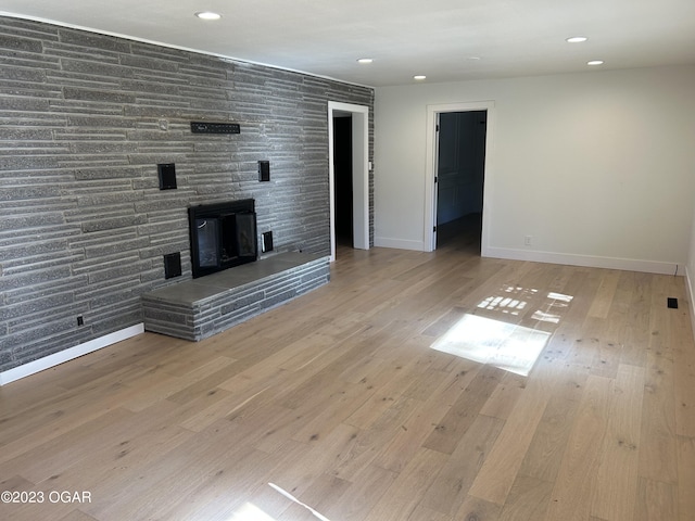 unfurnished living room with a wood stove and light wood-type flooring