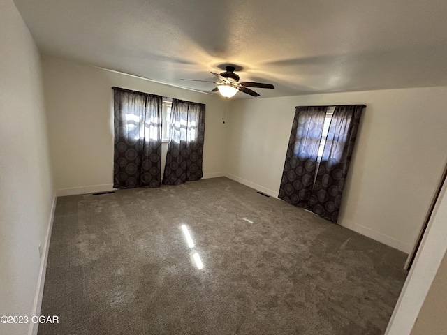 empty room with dark carpet and ceiling fan