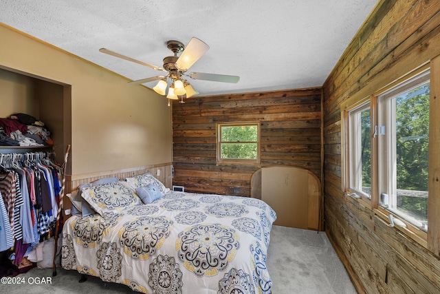 bedroom with carpet floors, wooden walls, multiple windows, and ceiling fan