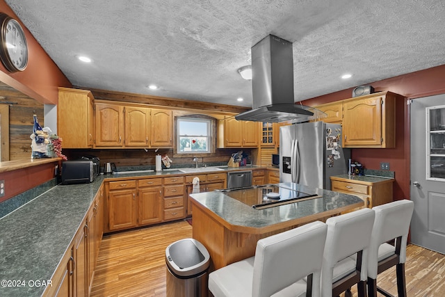 kitchen featuring a kitchen island, stainless steel appliances, island exhaust hood, light wood-type flooring, and a textured ceiling