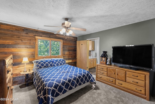 bedroom featuring carpet, wooden walls, a textured ceiling, and ceiling fan