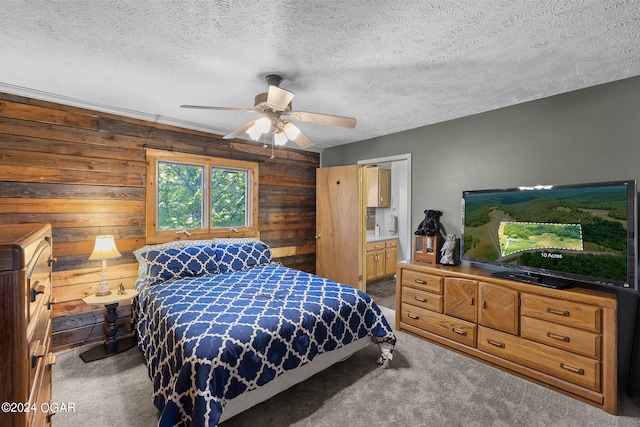 carpeted bedroom featuring wood walls, ceiling fan, and a textured ceiling