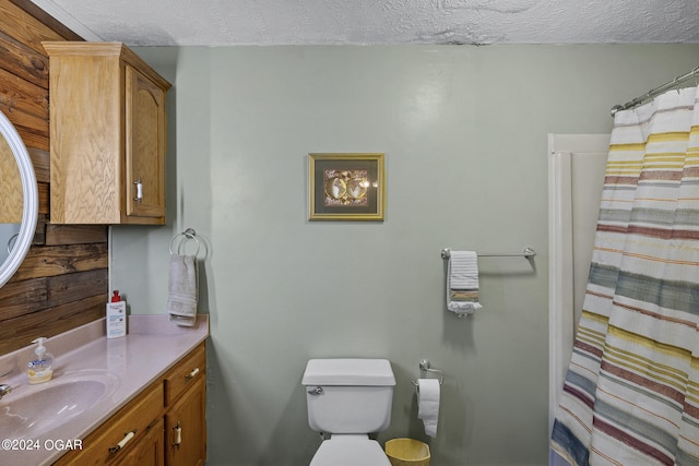 bathroom featuring a textured ceiling, toilet, and oversized vanity